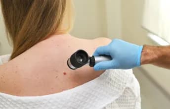 Uma paciente em ambiente hospitalar sendo examinada por um médico oncologista